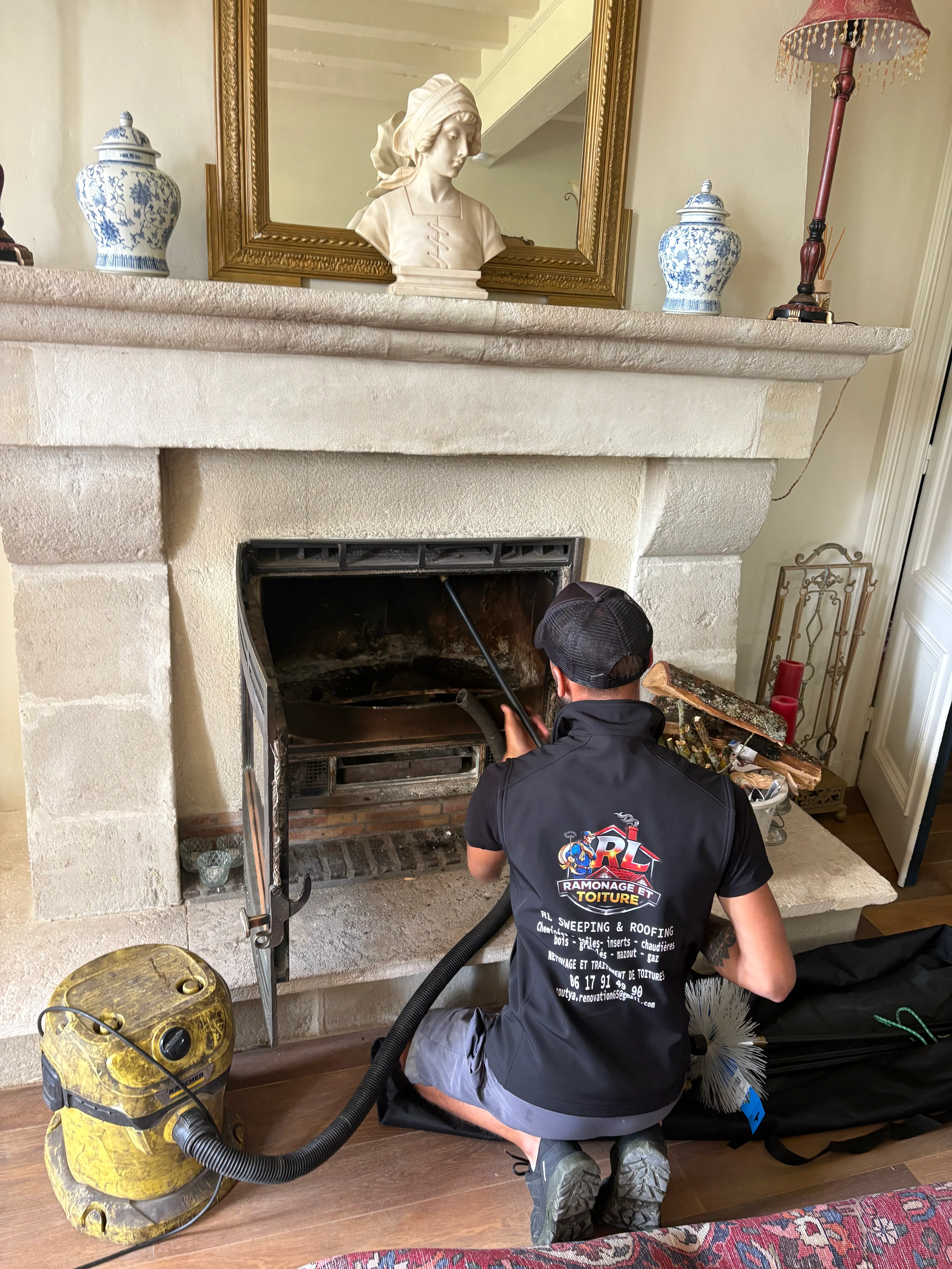 Artisan réalisant le nettoyage d'un foyer avec un aspirateur